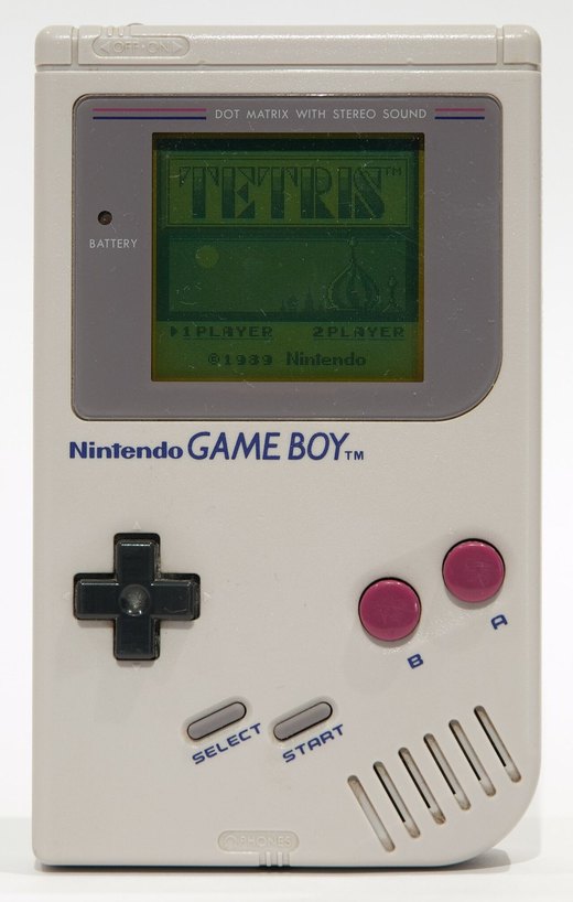 An original grey Nintendo Game Boy switched on, showing the Tetris title screen with 1 PLAYER and 2 PLAYER options and the 1989 Nintendo copyright line.