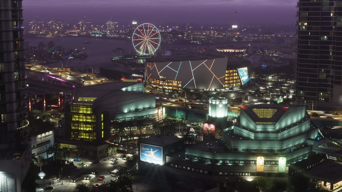 An aerial view of Vice City at dusk under a purple sky, with a lit ferris wheel, the Sahara Arena, illuminated tower blocks and busy freeways.
