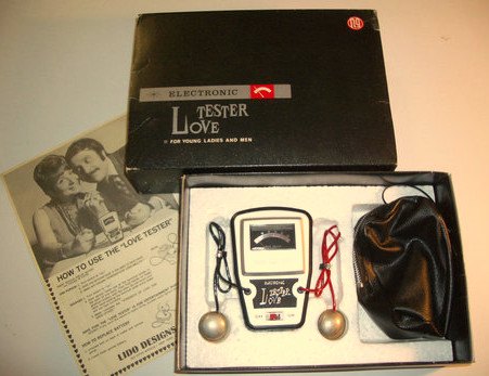 A boxed Nintendo Love Tester: a small meter unit with two metal hand-held spheres on red wires, an instruction leaflet and a pouch.