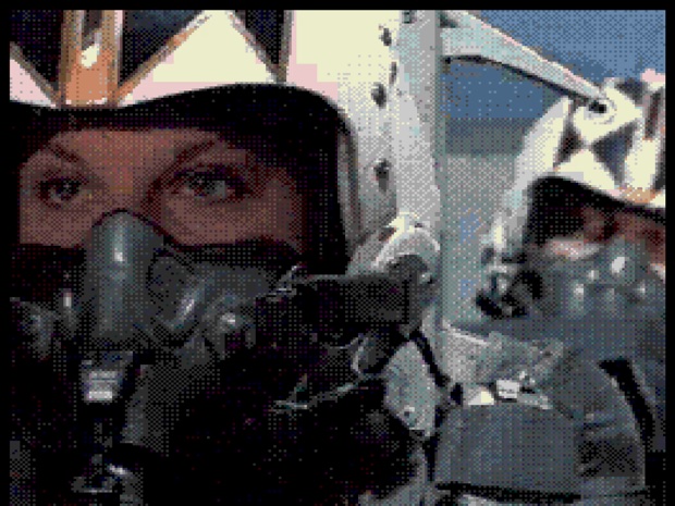 Tomcat Alley full motion video: a heavily dithered shot of a fighter pilot in a helmet and oxygen mask looking towards camera.