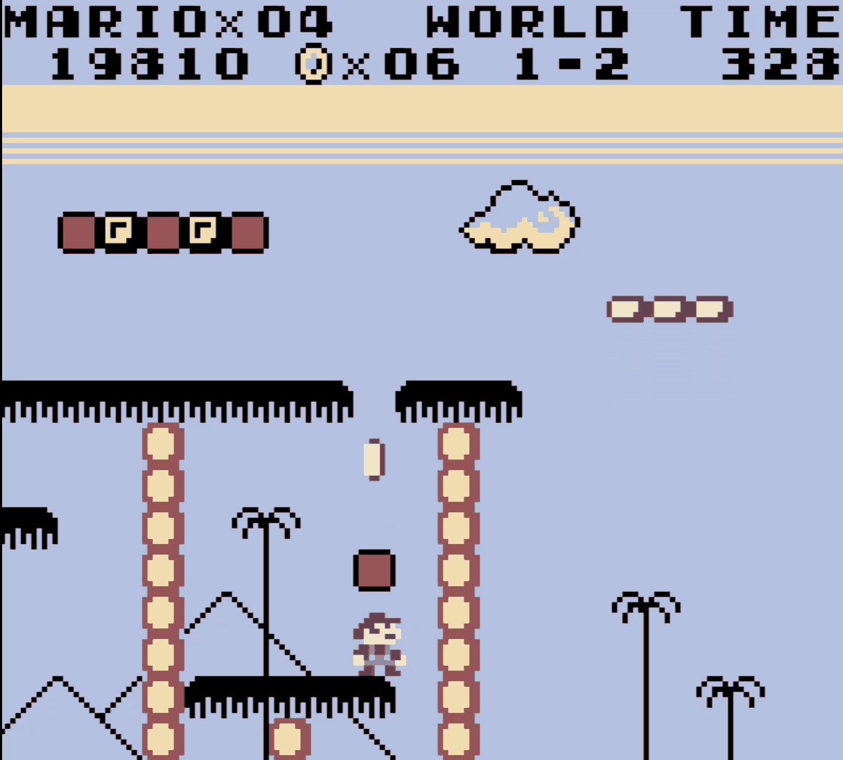 World 1-2 of Super Mario Land: Mario stands between two tall stone columns, with palm trees and pyramid outlines in the background.