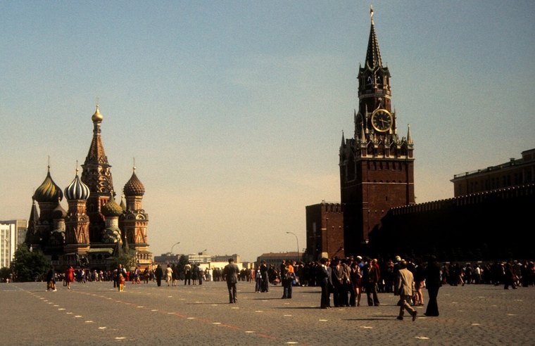 Red Square in Moscow in the 1980s, with St Basil's Cathedral on the left and the Spasskaya clock tower on the right, and crowds walking across the cobbles.