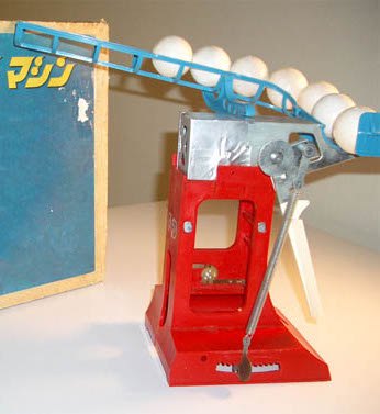 The Nintendo Ultra Machine: a red and blue mechanical baseball pitching toy with white plastic balls loaded in a chute, beside its box.